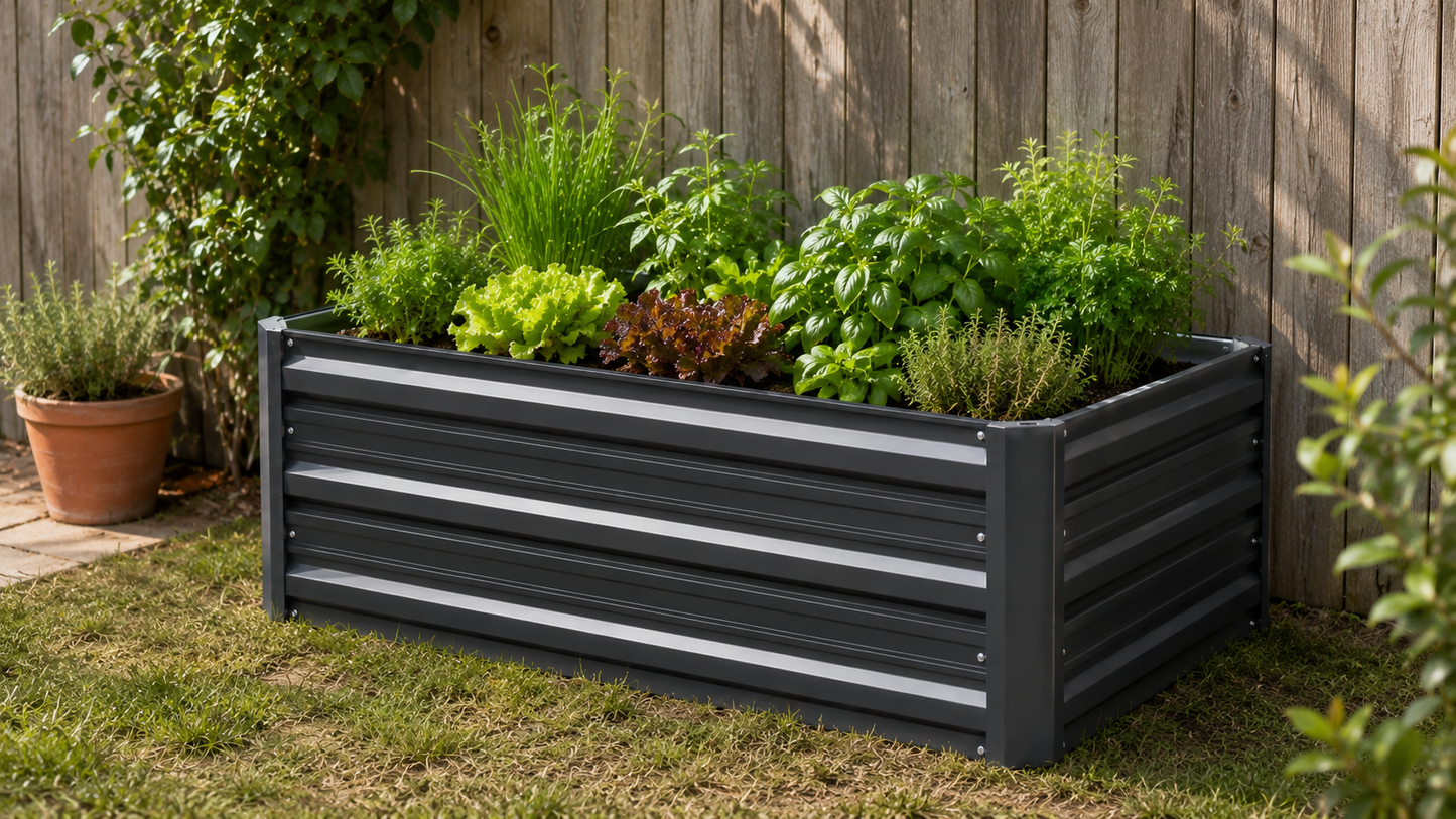 A rectangular black metal raised garden bed with horizontal slats, filled with various green herbs and plants, set on a grassy lawn in front of a wooden fence.