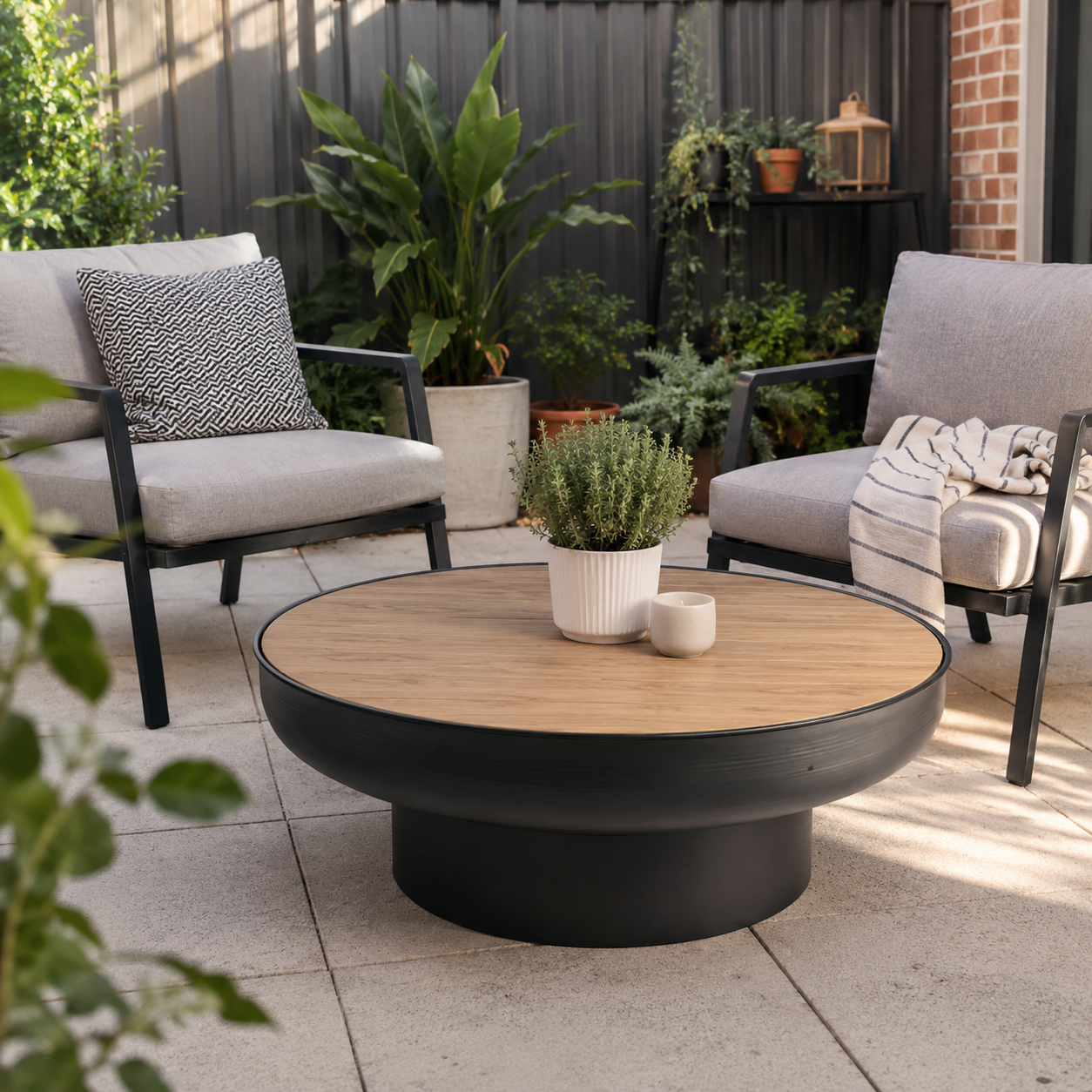 Outdoor patio setting with two gray chairs and a round wooden table on a tiled patio.
