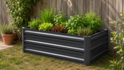 A rectangular black metal raised garden bed with horizontal slats, filled with various green herbs and plants, set on a grassy lawn in front of a wooden fence.