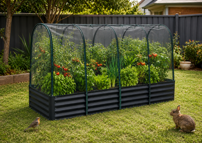 A black corrugated metal raised garden bed with a semi-transparent arched mesh tunnel cover, filled with green plants and red flowers, set in a grassy backyard with a bird and rabbit nearby.