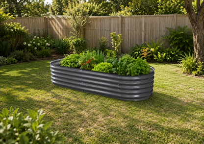 A dark gray corrugated metal raised garden bed filled with green plants, situated on a grassy lawn in a backyard with a wooden fence and trees in the background.