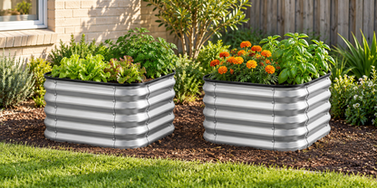 Two galvanized corrugated metal raised garden beds filled with green plants and orange marigold flowers, placed on mulch in a backyard garden setting next to a brick house.
