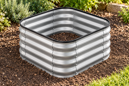 A square galvanized steel raised garden bed with a corrugated metal design, filled with soil and placed in a garden bed with mulch and plants.