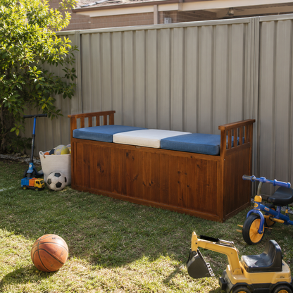 Wooden storage seat in backyard with toys surrounding it.