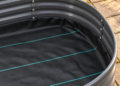 Close-up of a black corrugated metal tub liner with a black mesh bottom and bright teal stitching, shown on an outdoor paved surface.