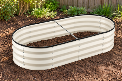 An oval raised garden bed made of corrugated metal, filled with soil, set in a garden with mulch and plants in the background.